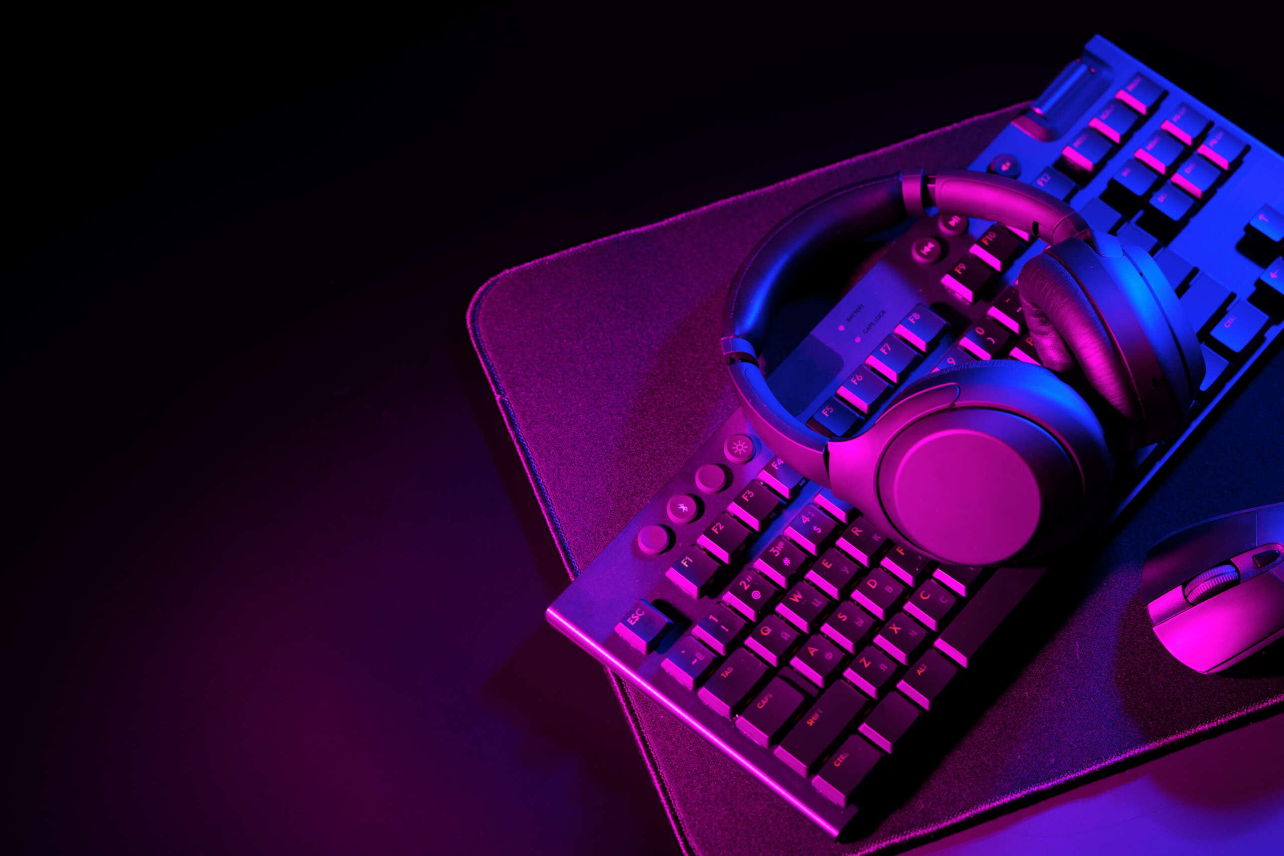 Headphones, computer mouse and keyboard on black background